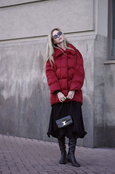 a lady in a red down coat and a black long pleated skirt